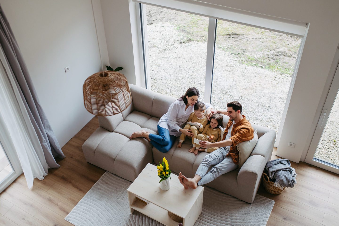 Top view of nuclear family with small daughters sitting on sofa in their home.