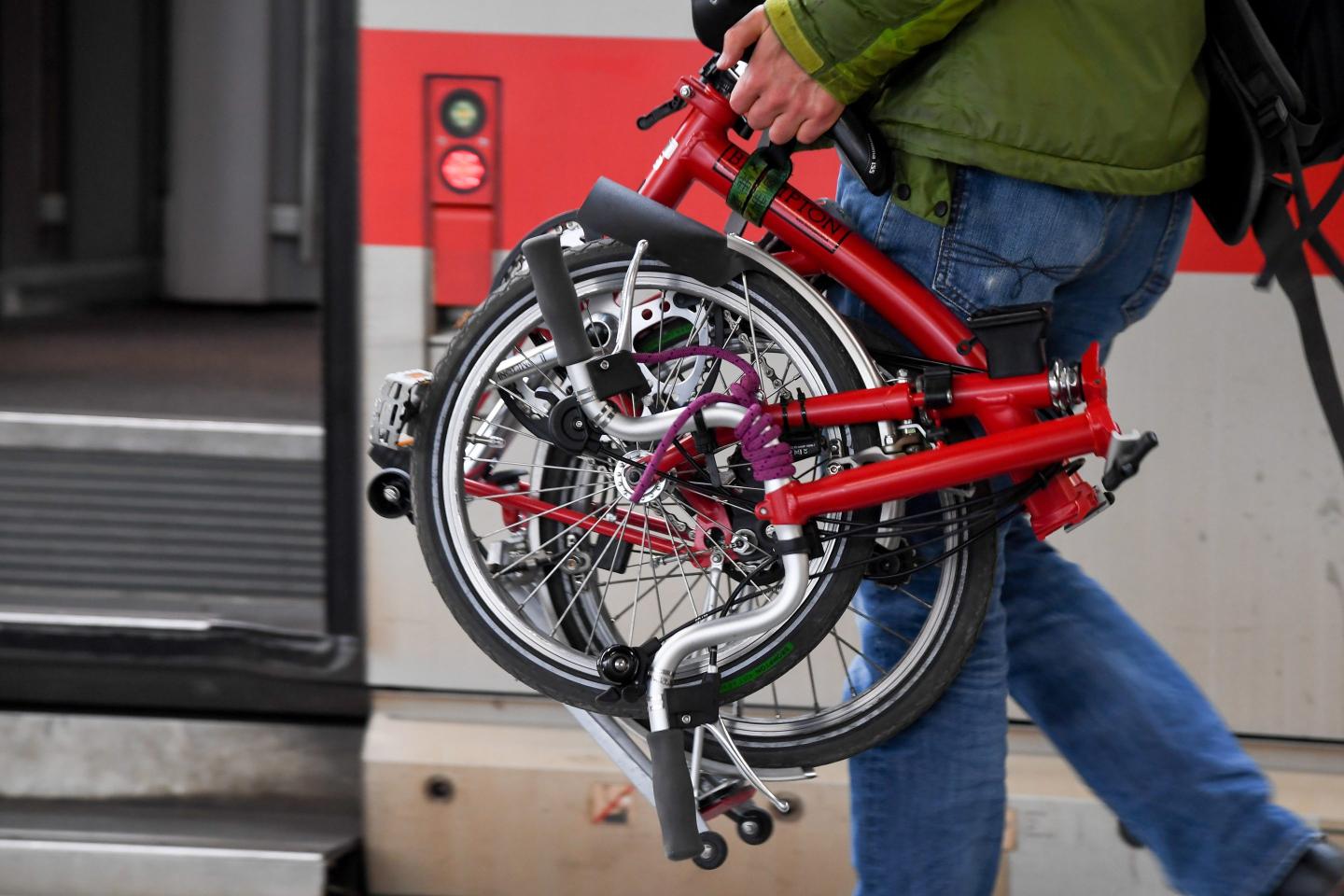 A passenger carries the folding bike classic Brompton on the platform at Munich Central Station.