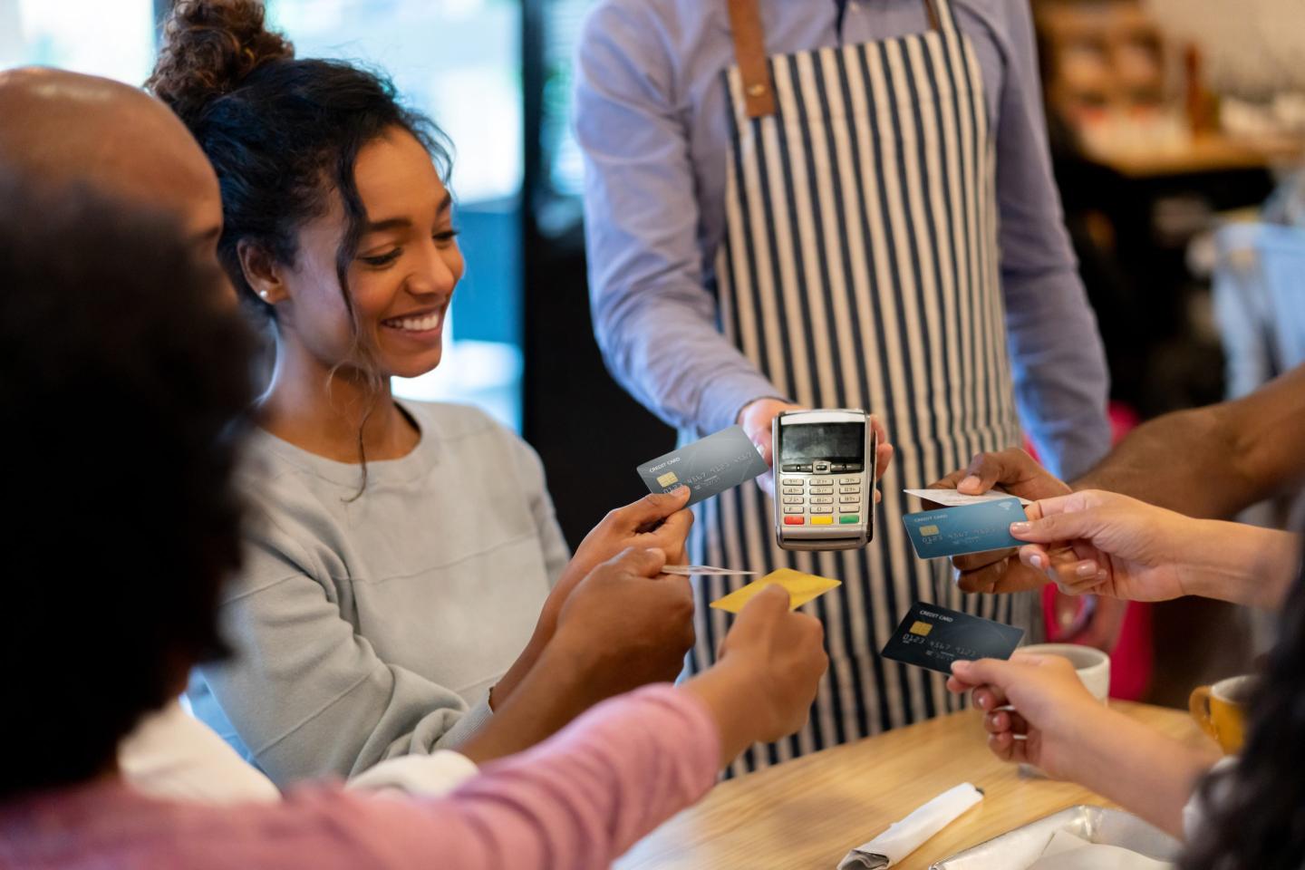 Group of people presenting cards to a payment machine.