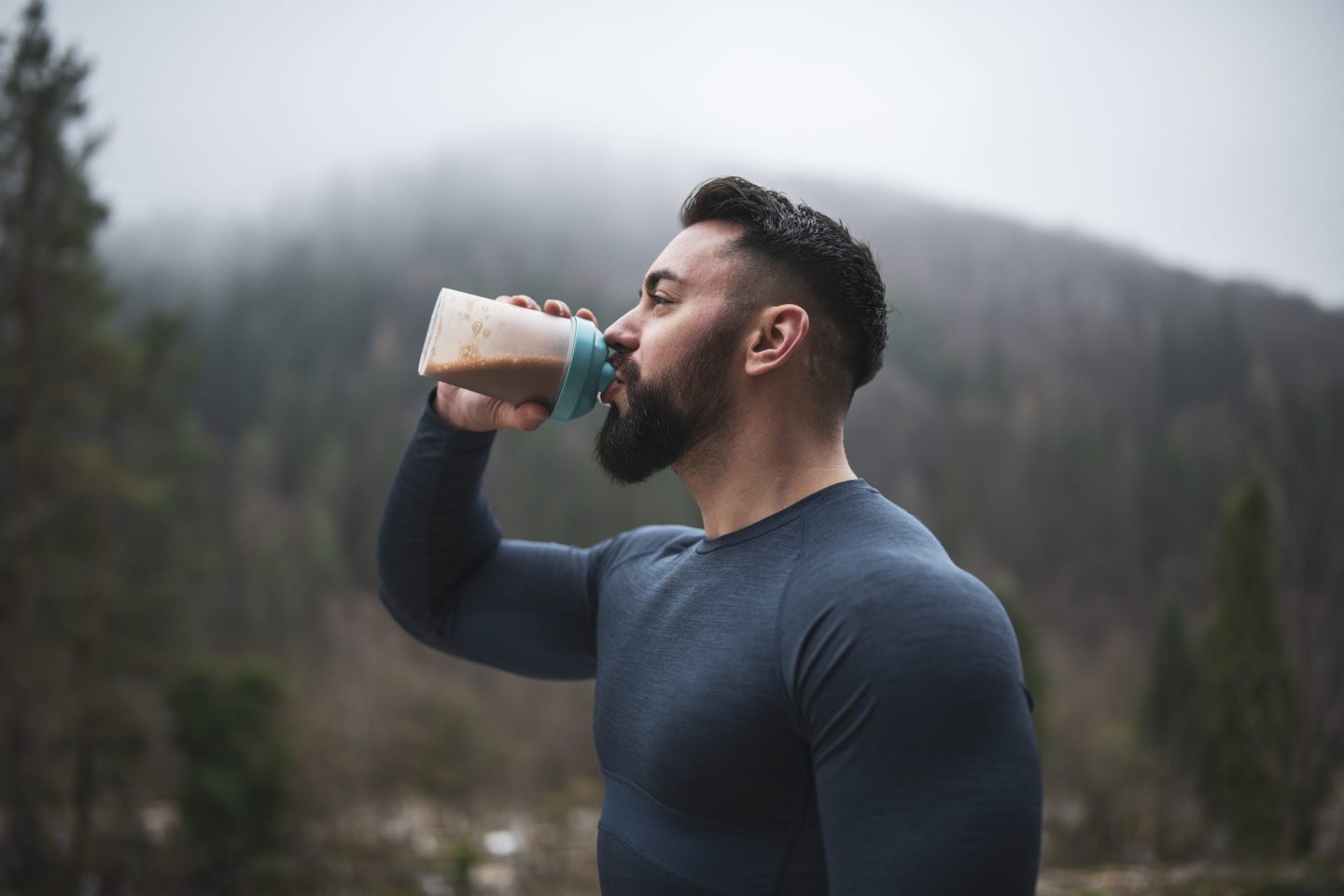 Muscled man drinks protein shake outside