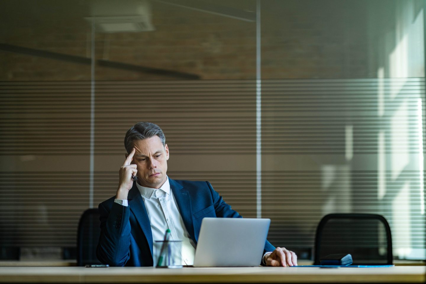 A man sits at his desk with his head propped on his hand.