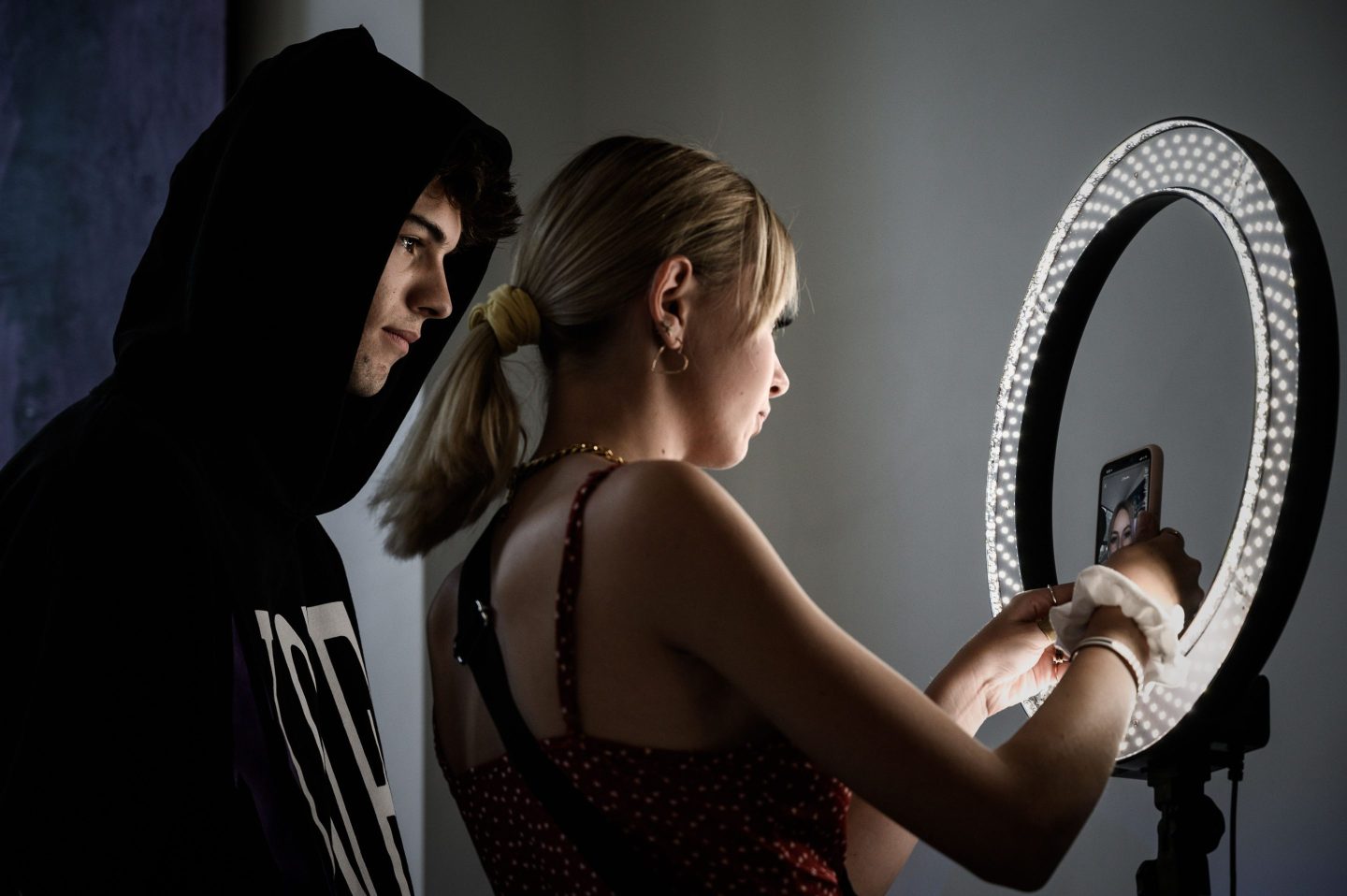 Young man and woman stand in front of ring light camera to record video