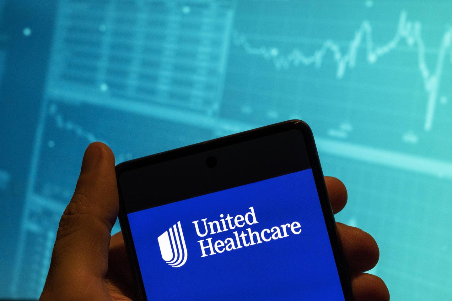 The UnitedHealthcare logo on a phone in front of some type of finance-y looking background