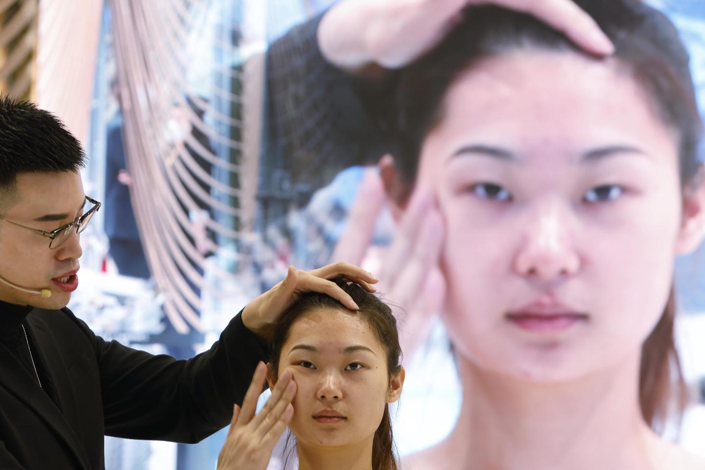 A staff member applies makeup to a model at the Estee Lauder booth in Shanghai