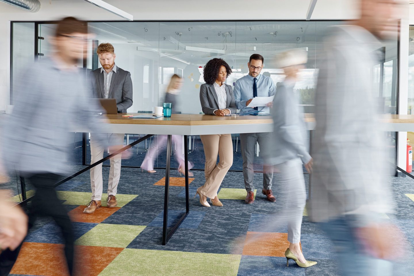 Workers at office while others rush around them.