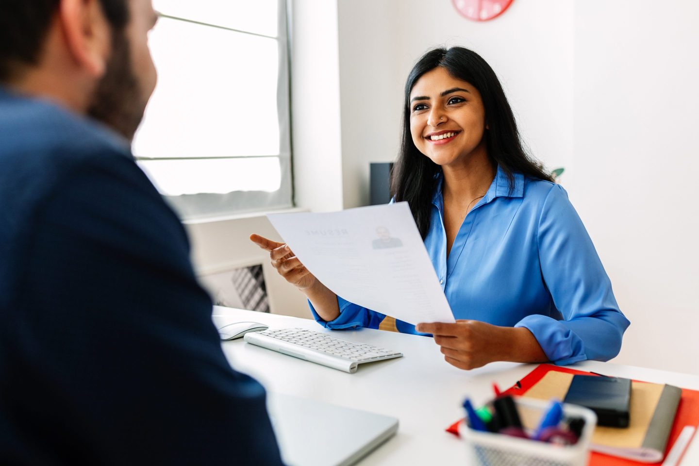 female office worker and male office worker look at a resume sitting at a desk
