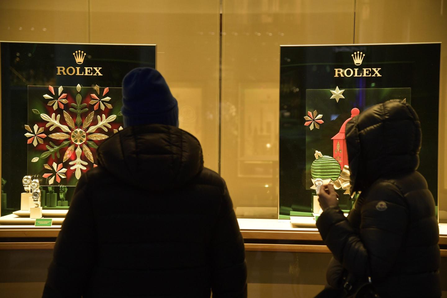 A bundled-up shopper looks at a Rolex holiday display window.