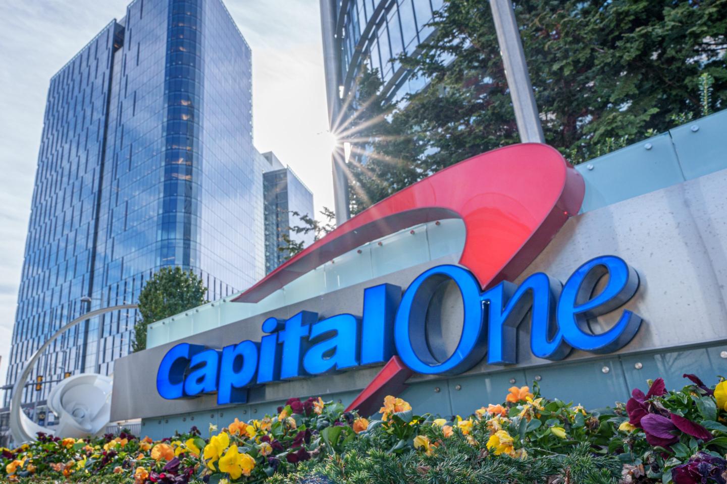 The sun flares over the top of the Capital One logo outside of their corporate headquarters
