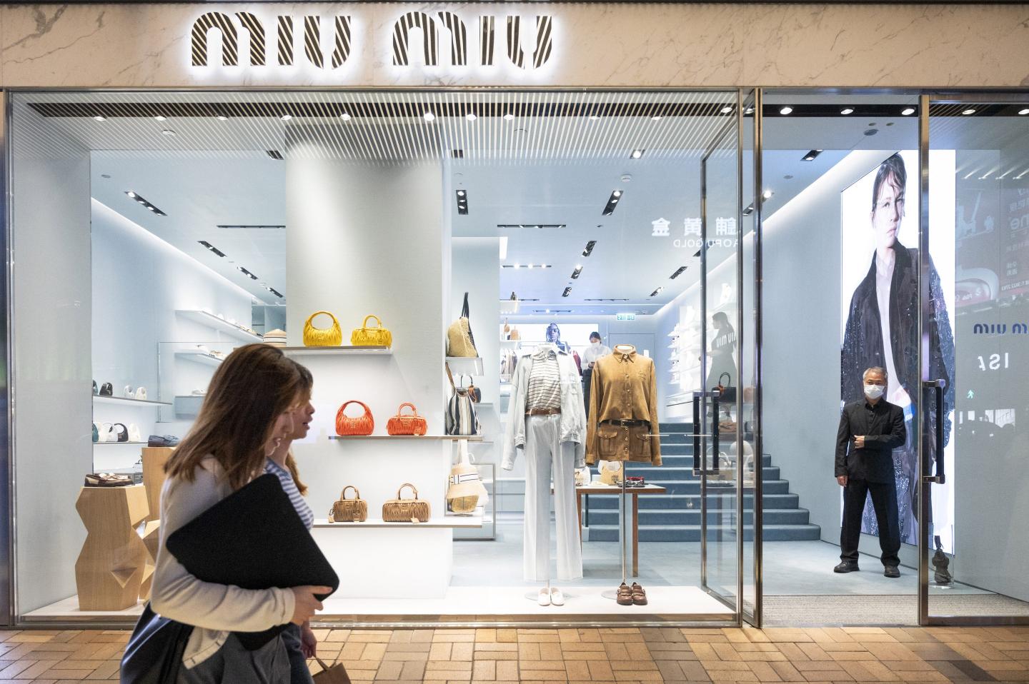 people walking past a Miu Miu store