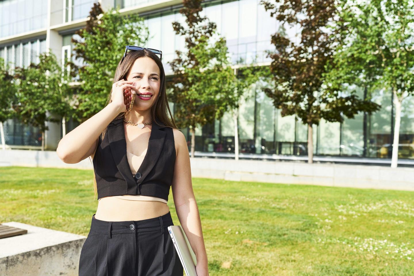 Worker in edgy outfit is on phone outside of office.