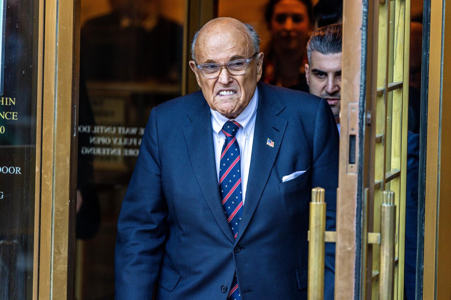 Rudy Giuliani exits a federal courthouse, grimacing
