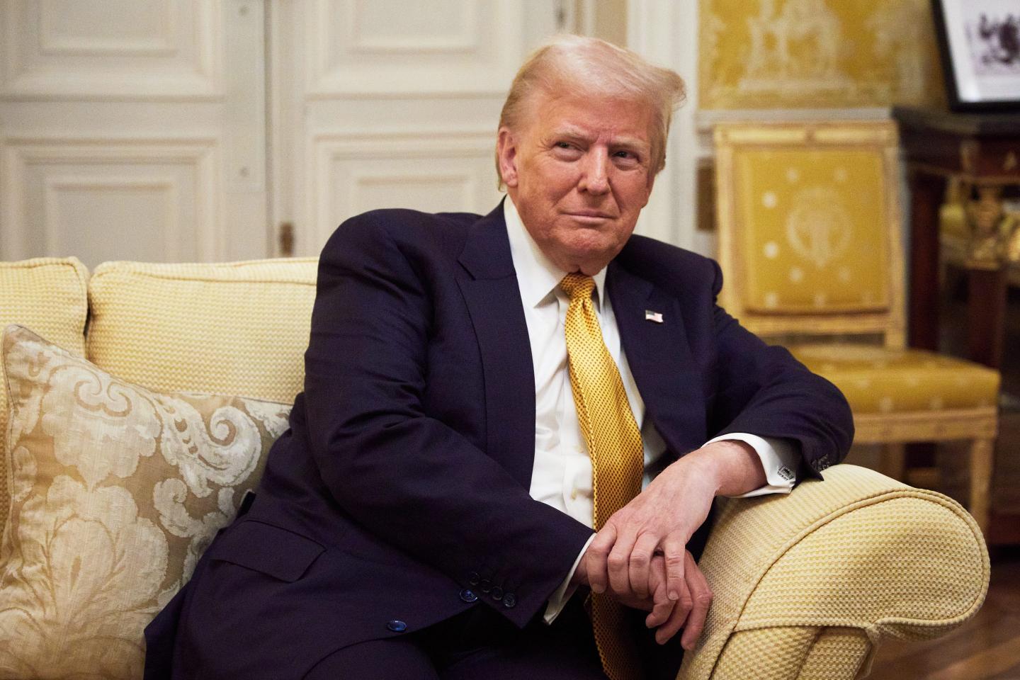 Donald Trump sitting on a yellow couch wearing a gold tie