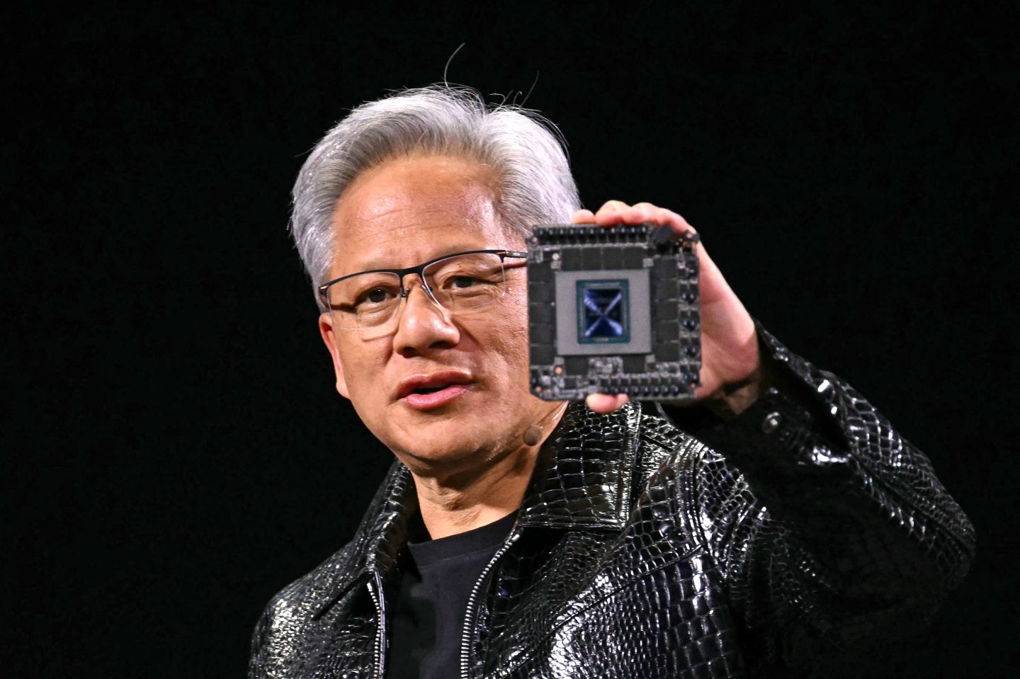 Nvidia CEO Jensen Huang holding an Nvidia GPU chip used for AI applications.