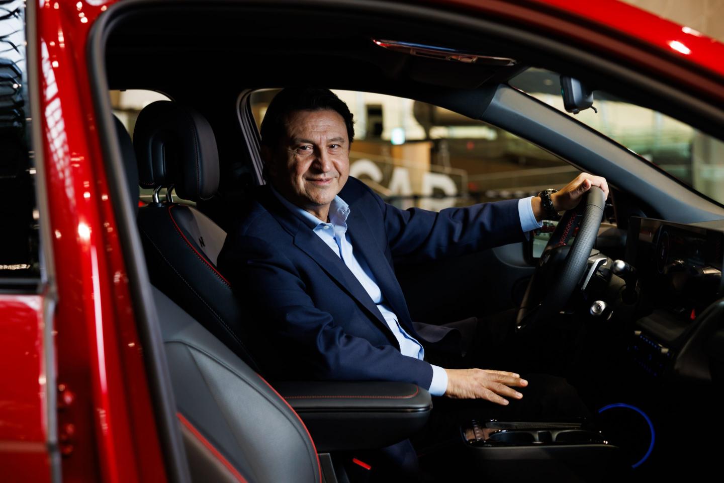 Hyundai CEO Jose Munoz poses in a red vehicle
