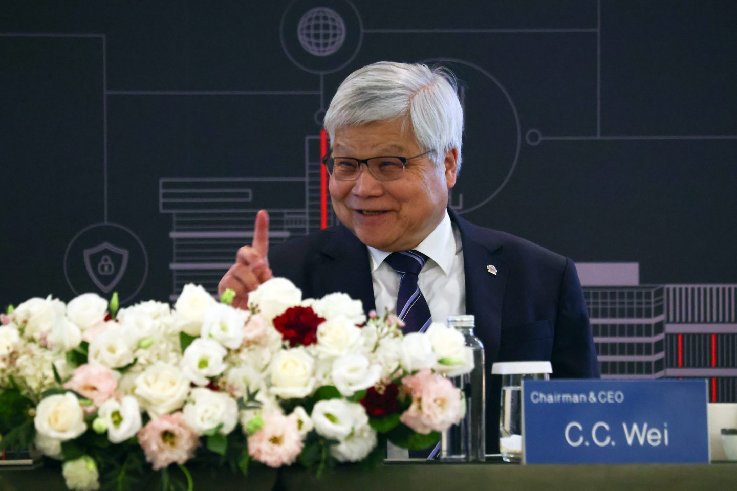 TSMC CEO C.C. Wei smiles and points his right index finger up as he talks during a news conference.