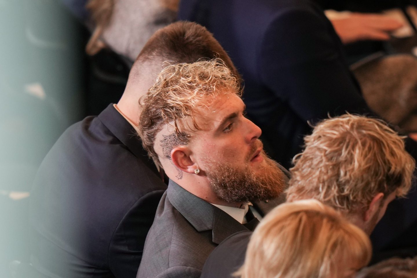 Jake Paul sits among of a row of people, looking up