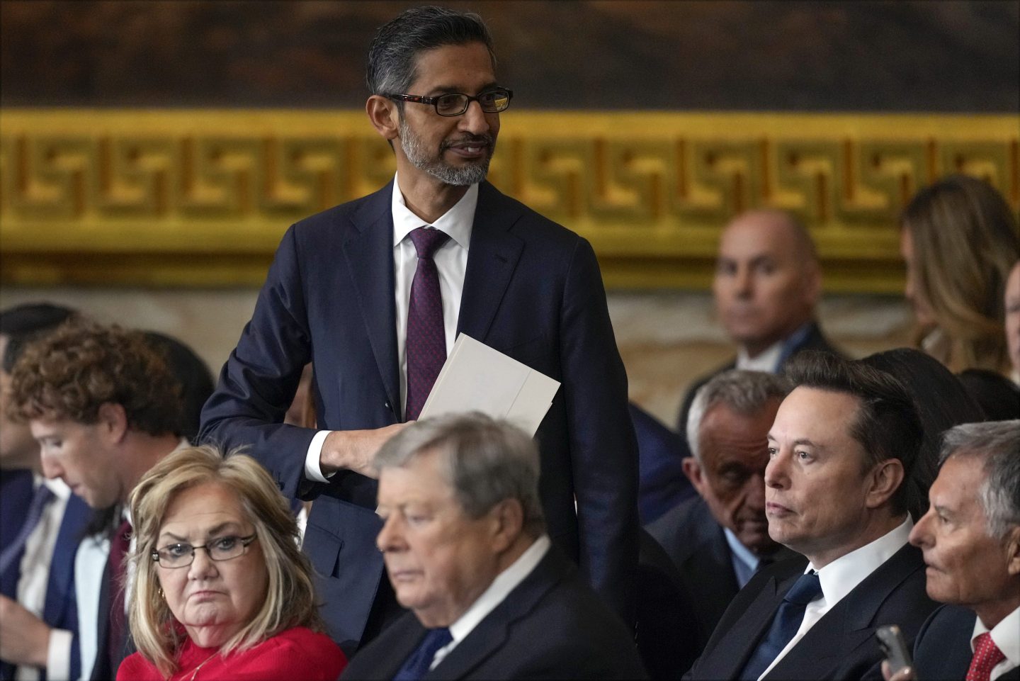 Sundar Pichai wears a suit and stands above a crowd of people in the U.S. Capitol building.
