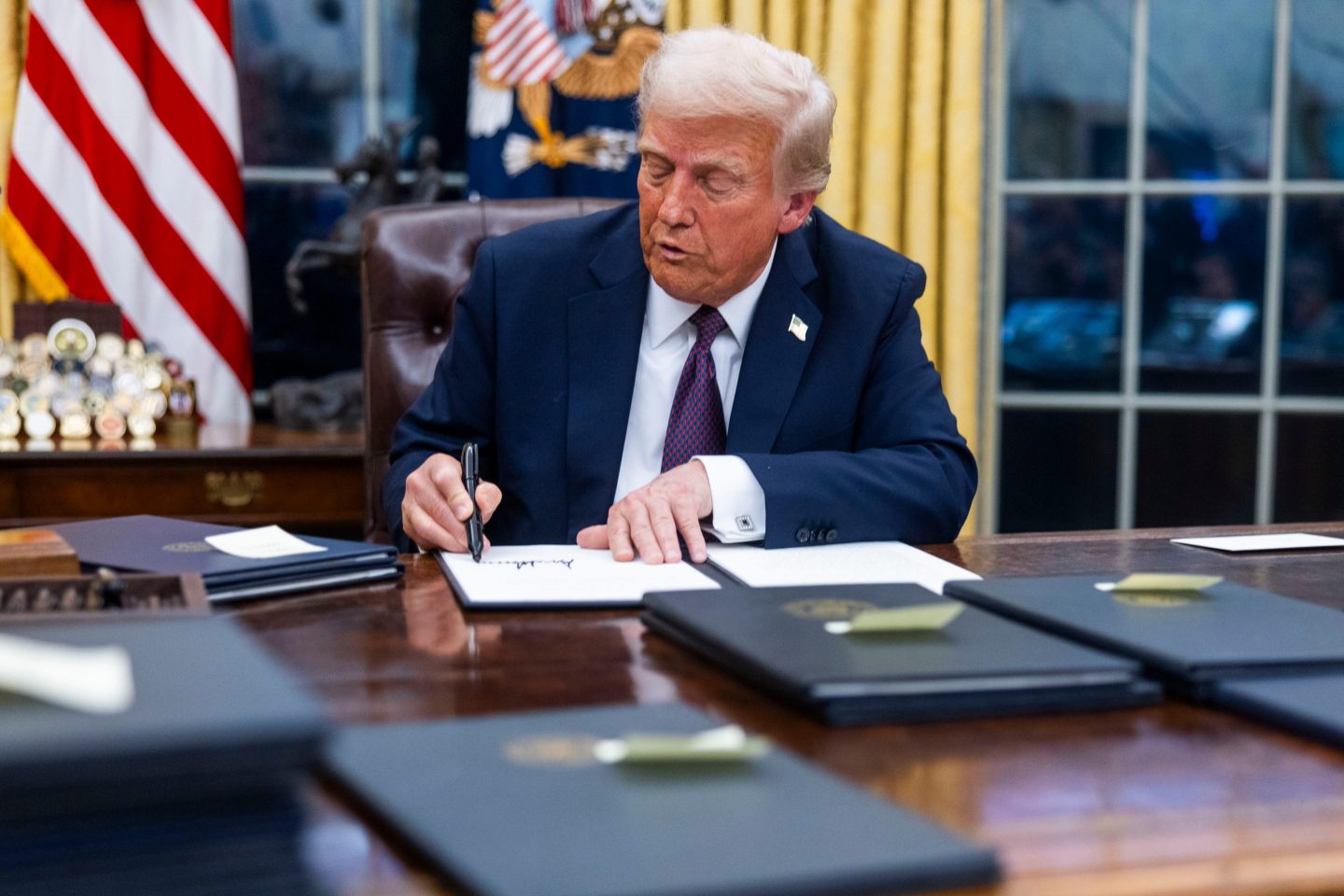 President Donald Trump signs a series of executive orders in the Oval Office on Monday, the first day of his second term.