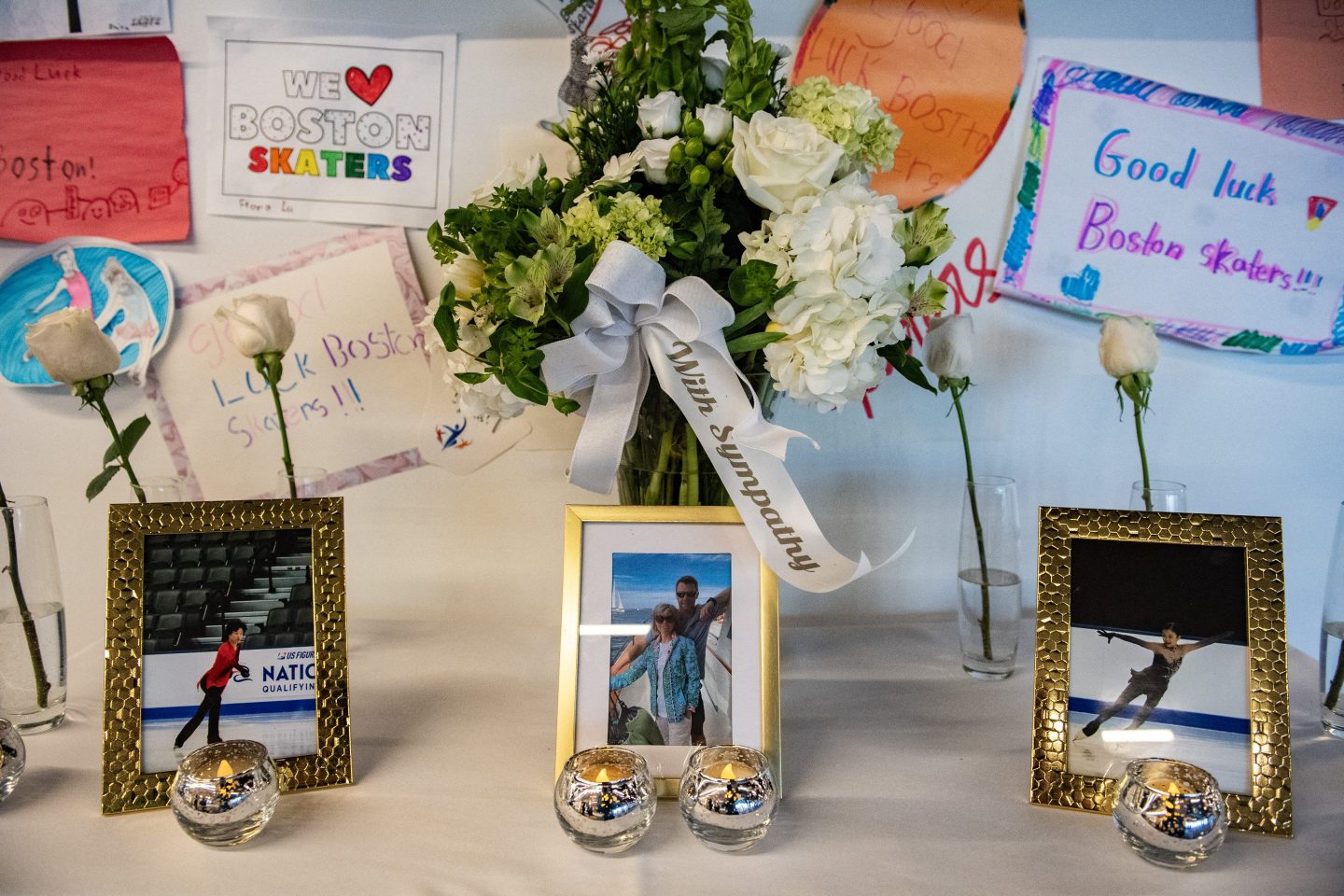 Sympathy flowers sit on a table alongside photos of people lost on American Airlines flight 5342
