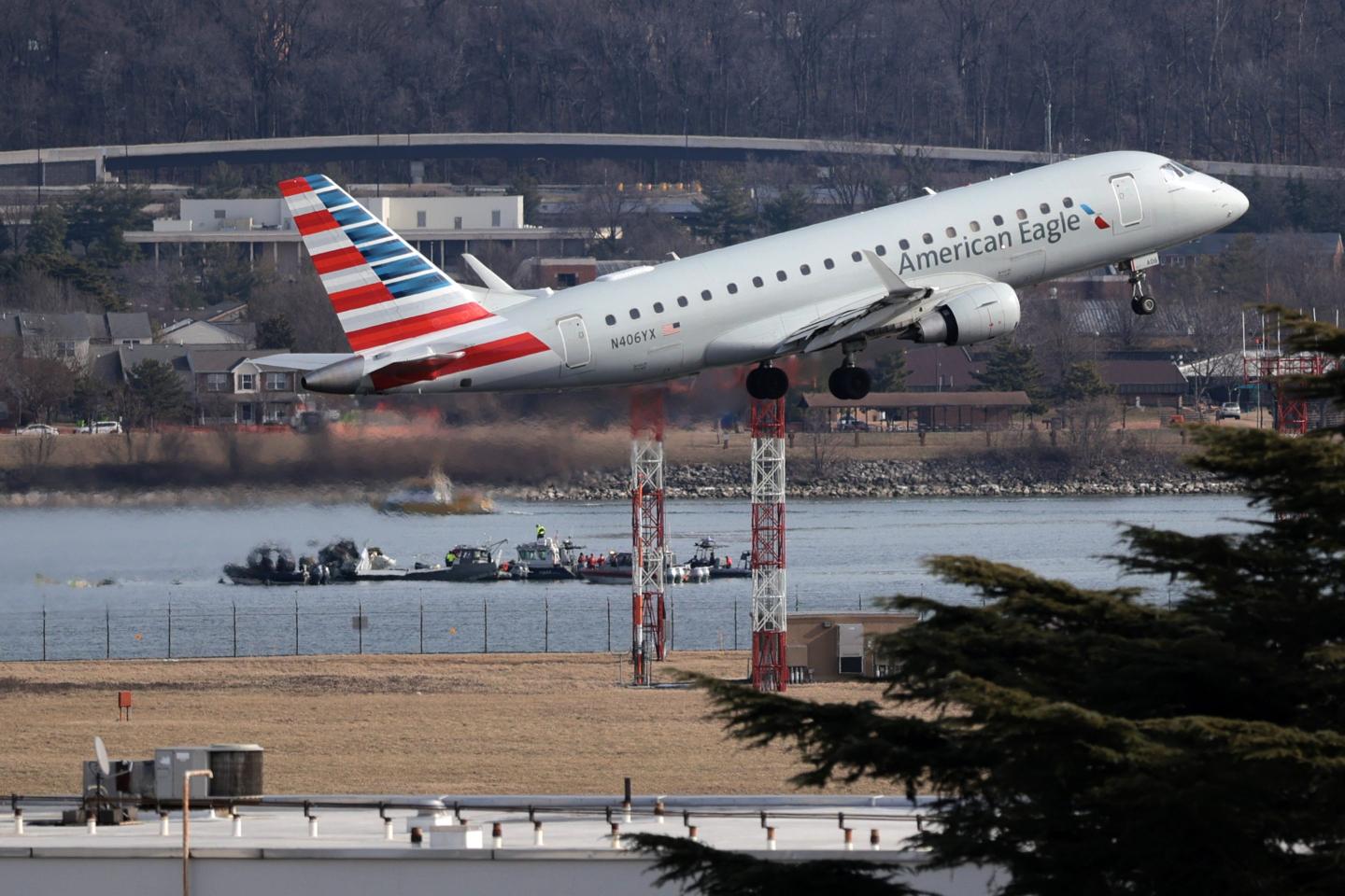 An American Eagle flight takes off from Reagan National Airport near where emergency crews work in the Potomac River on the crash site of an American Airlines plane