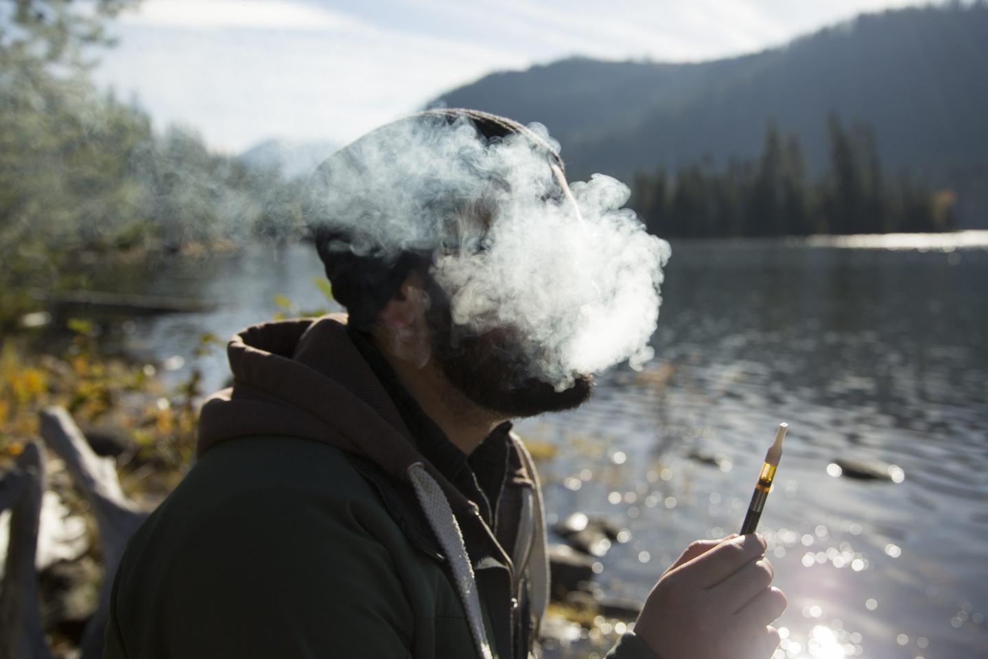 Man exhales smoke while legally smoking weed with a vape pen