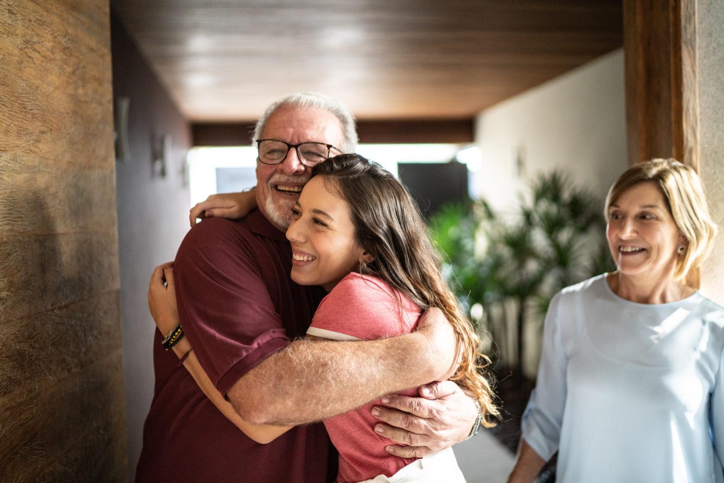 Granddaughter embracing grandfather at home