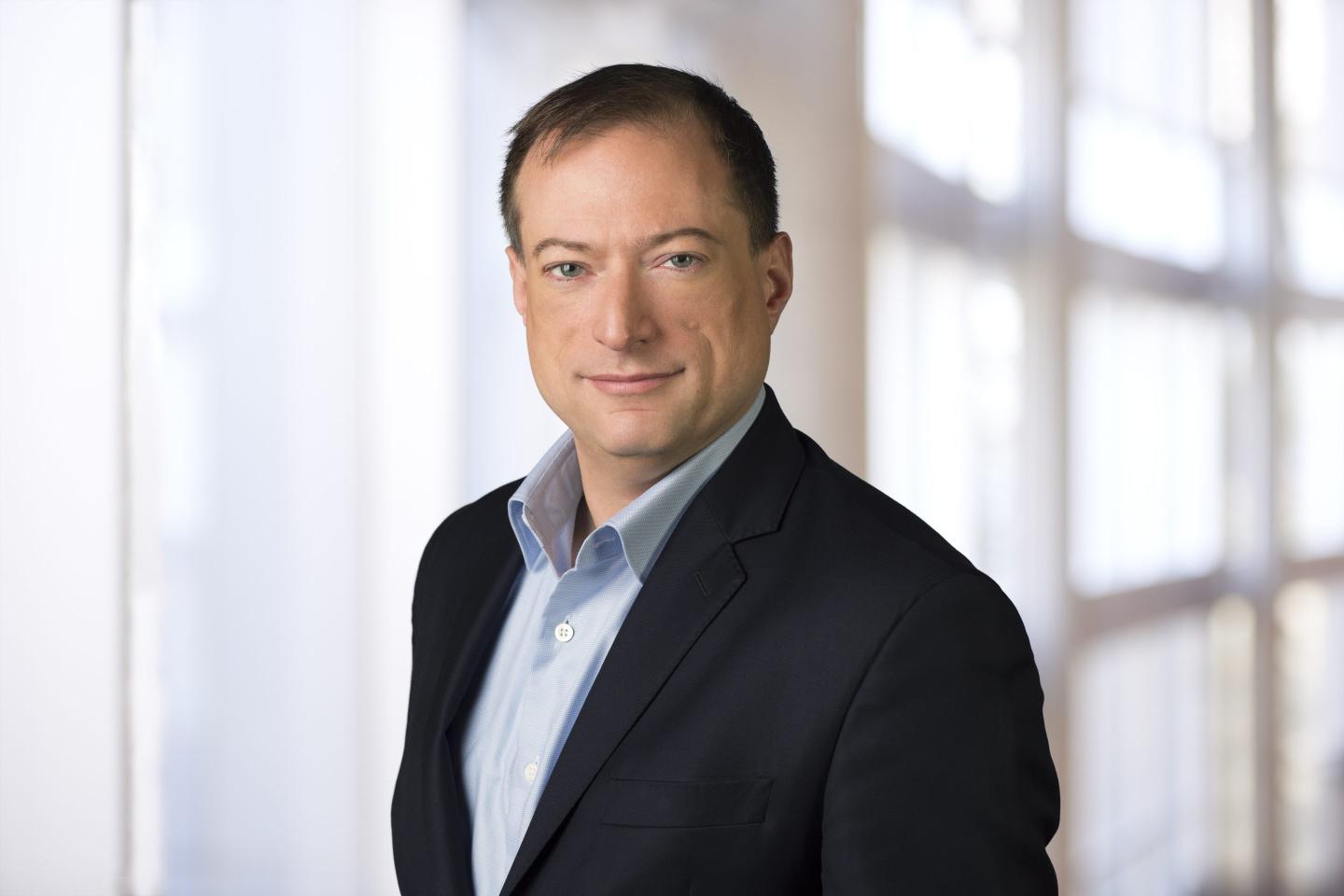 middle-aged man wearing blue shirt and suit jacket poses for a photo portrait