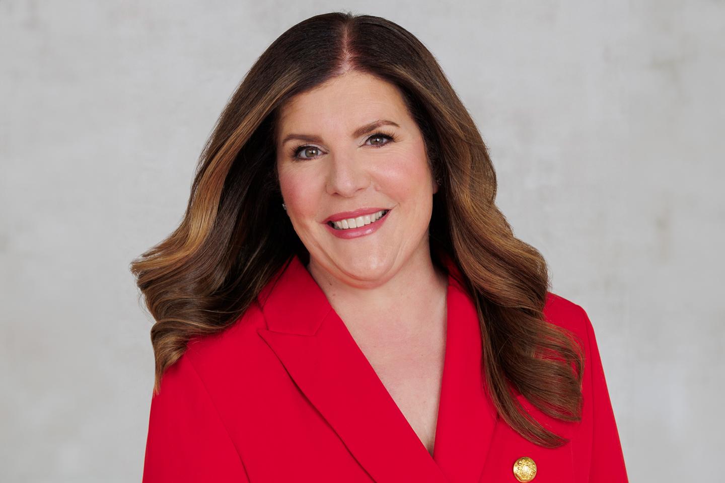 photo portrait of woman with brown hair wearing a red suit jacket