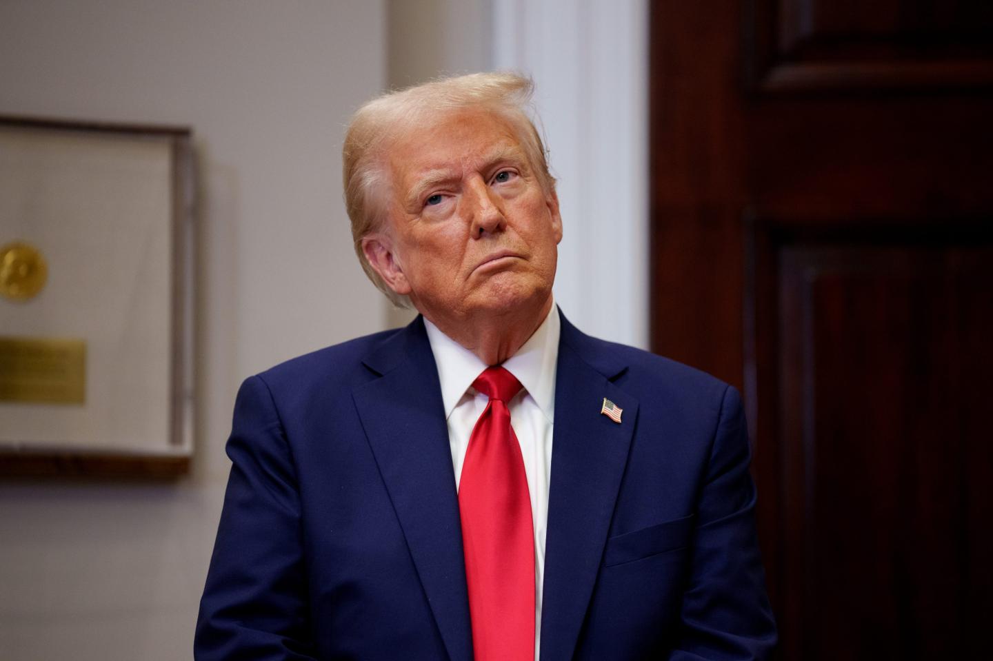 Trump stands with his head cocked to the right