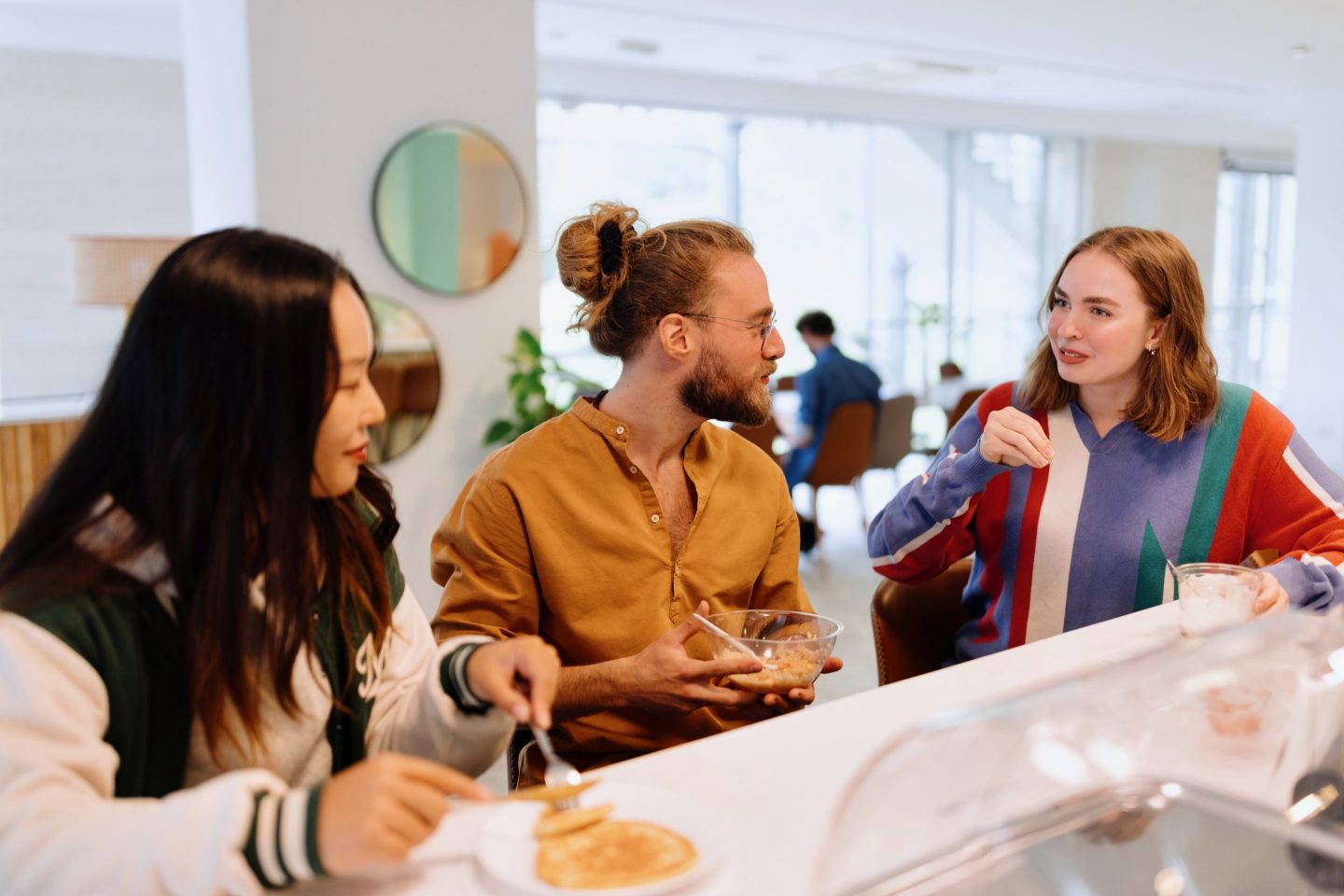 Coworkers eating at office cafeteria kitchen during lunch break.