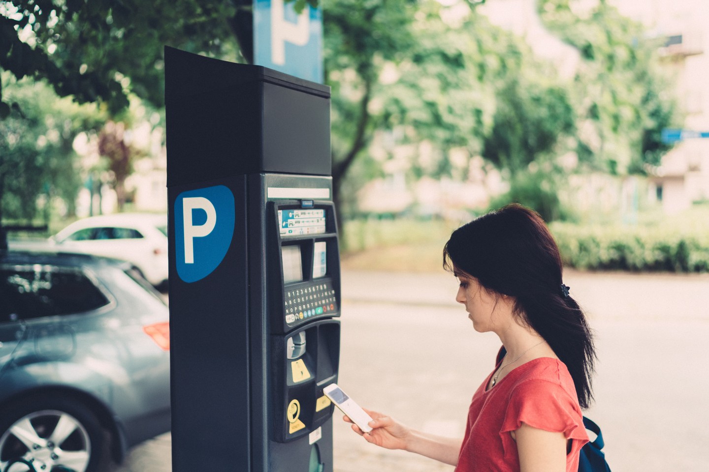 Woman in the city making mobile payment for parking place
