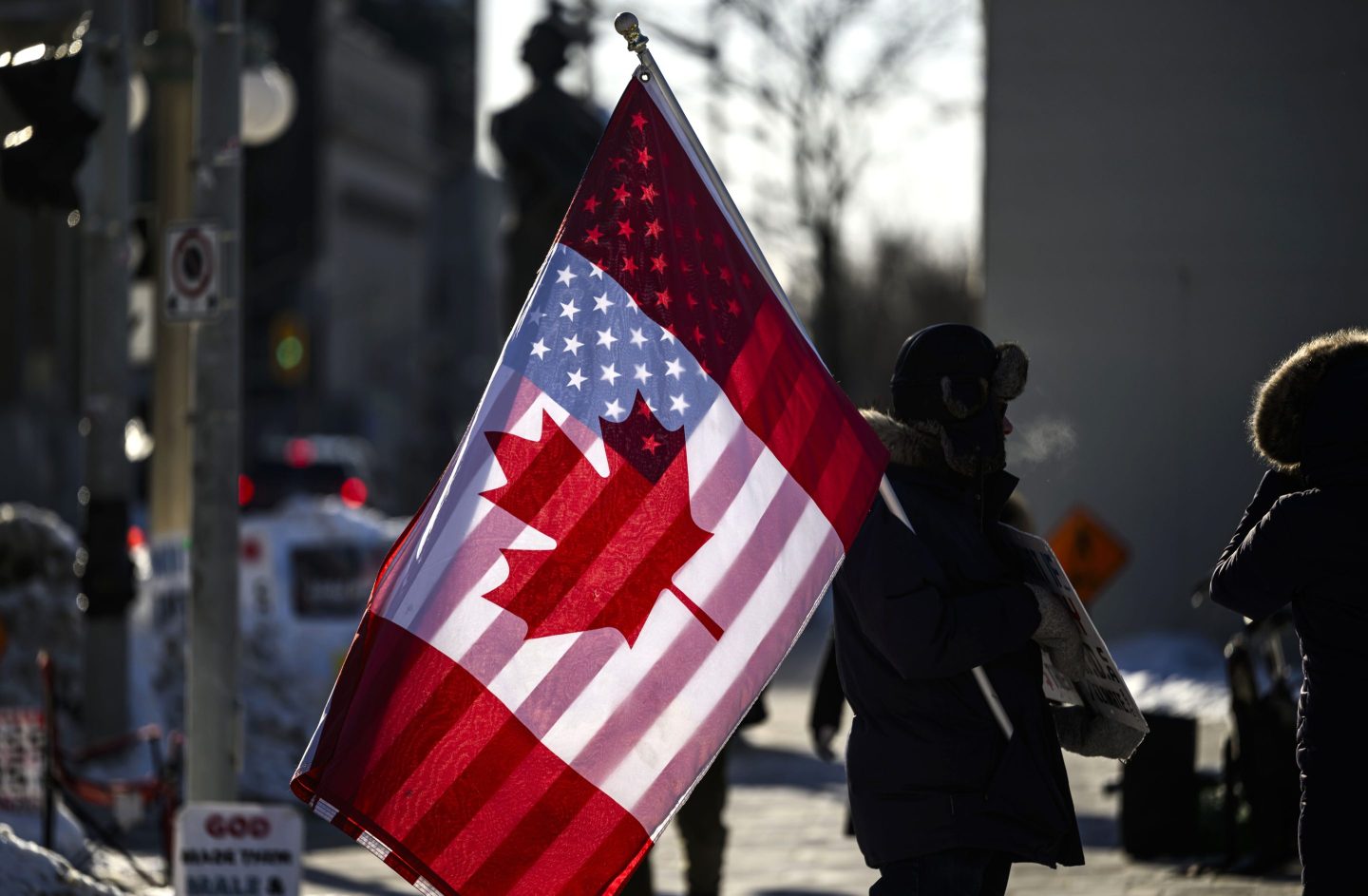 A protester holds the flags of Canada and the United States outside on Parliament Hill in Ottawa, on Feb. 1, 2025.