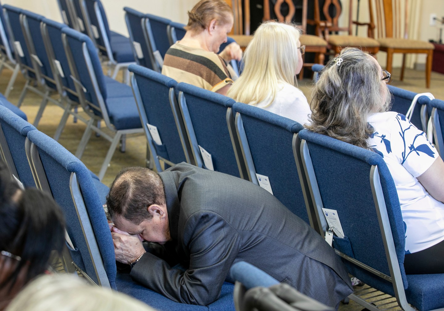 A Latino man clasps his hands in prayer during a church service