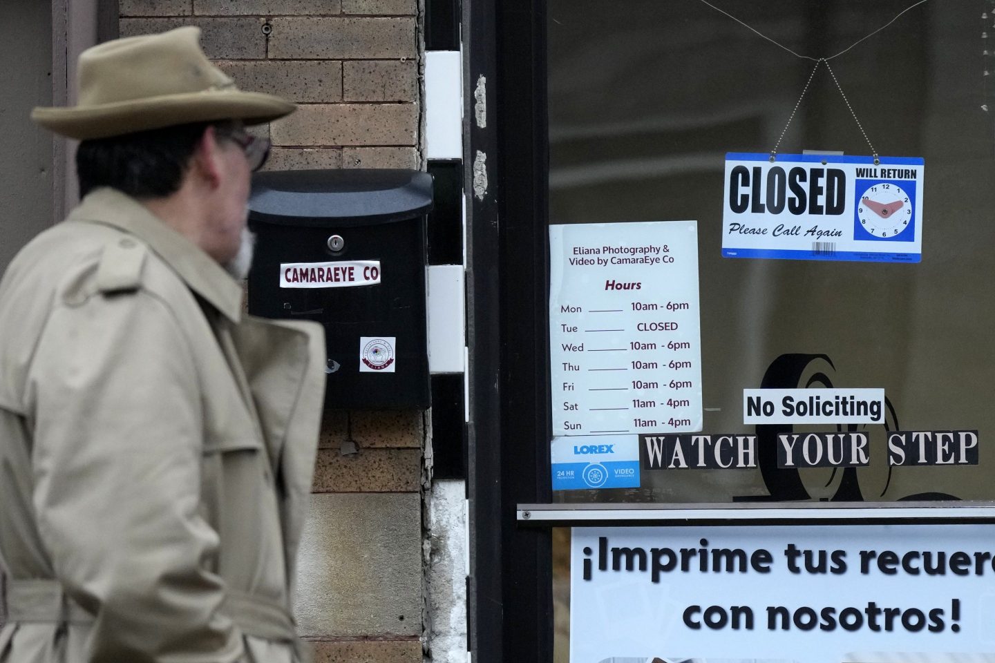 A pedestrian looks at signs displayed on the front door of a store in the Little Village neighborhood of Chicago, on Feb. 3, 2025.