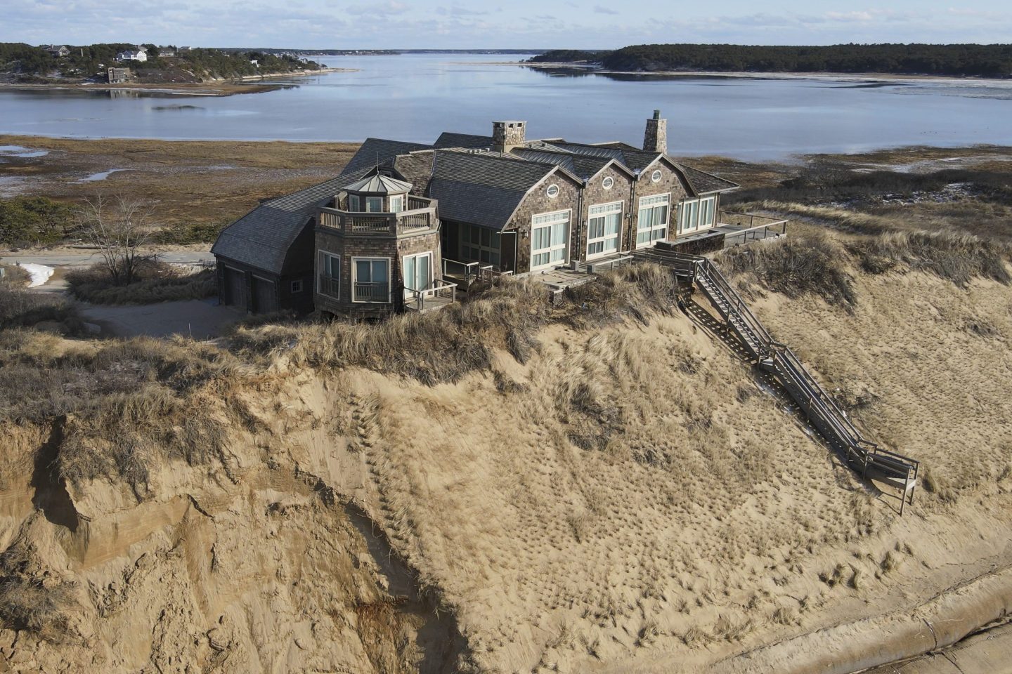A home sits atop of a sandy bluff overlooking a beach in Wellfleet, Mass