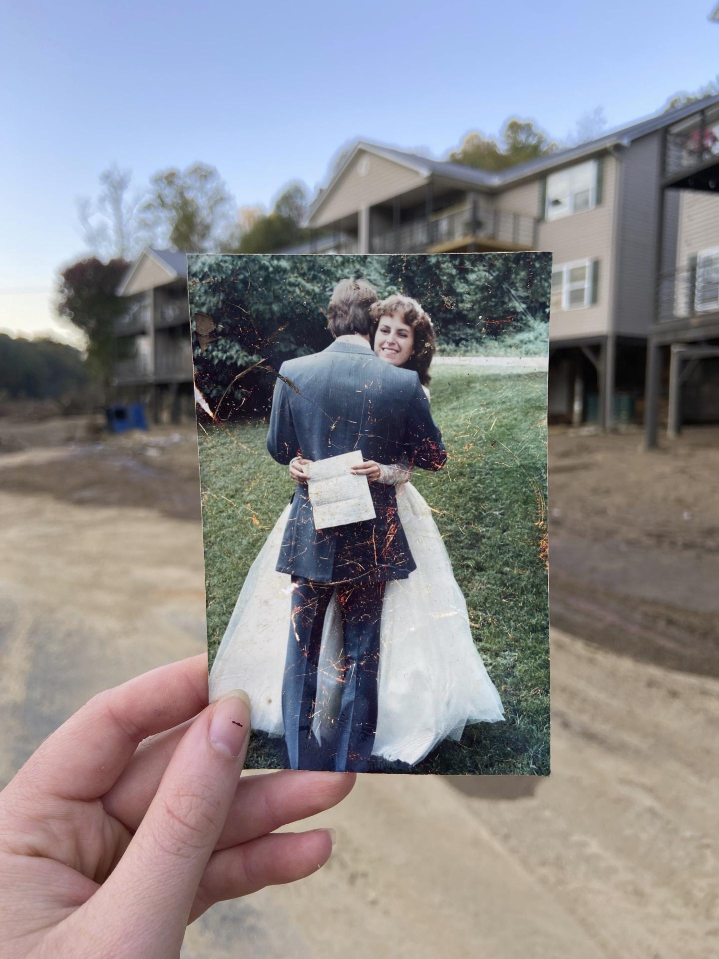 A hand holds a photo of a bride and groom