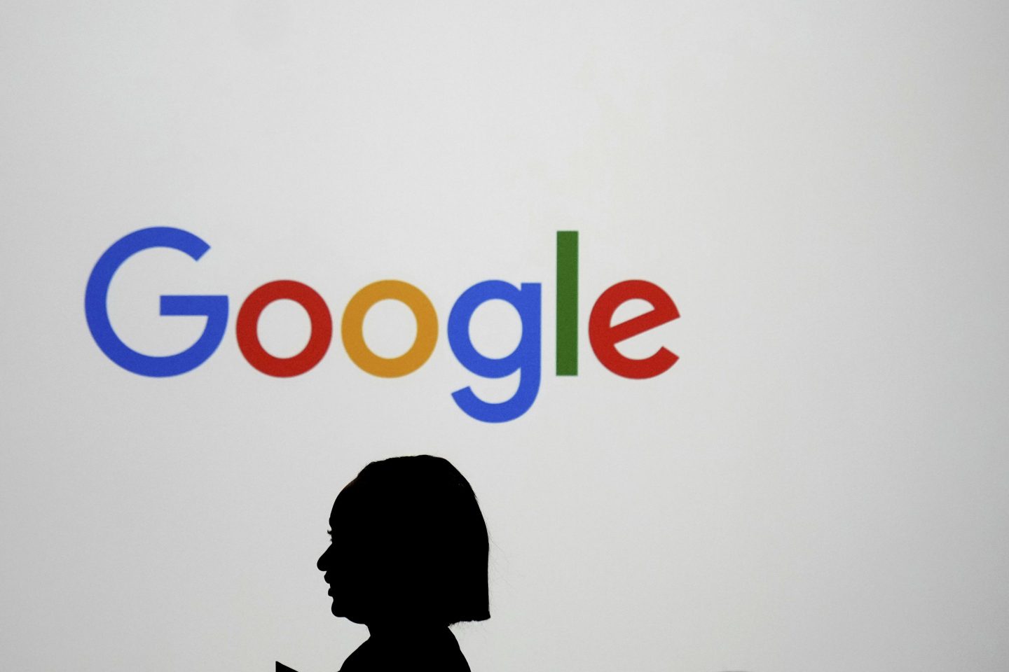 A woman walks by a giant screen with a logo at an event at the Paris Google Lab on the sidelines of the AI Action Summit in Paris, Feb. 9, 2025.