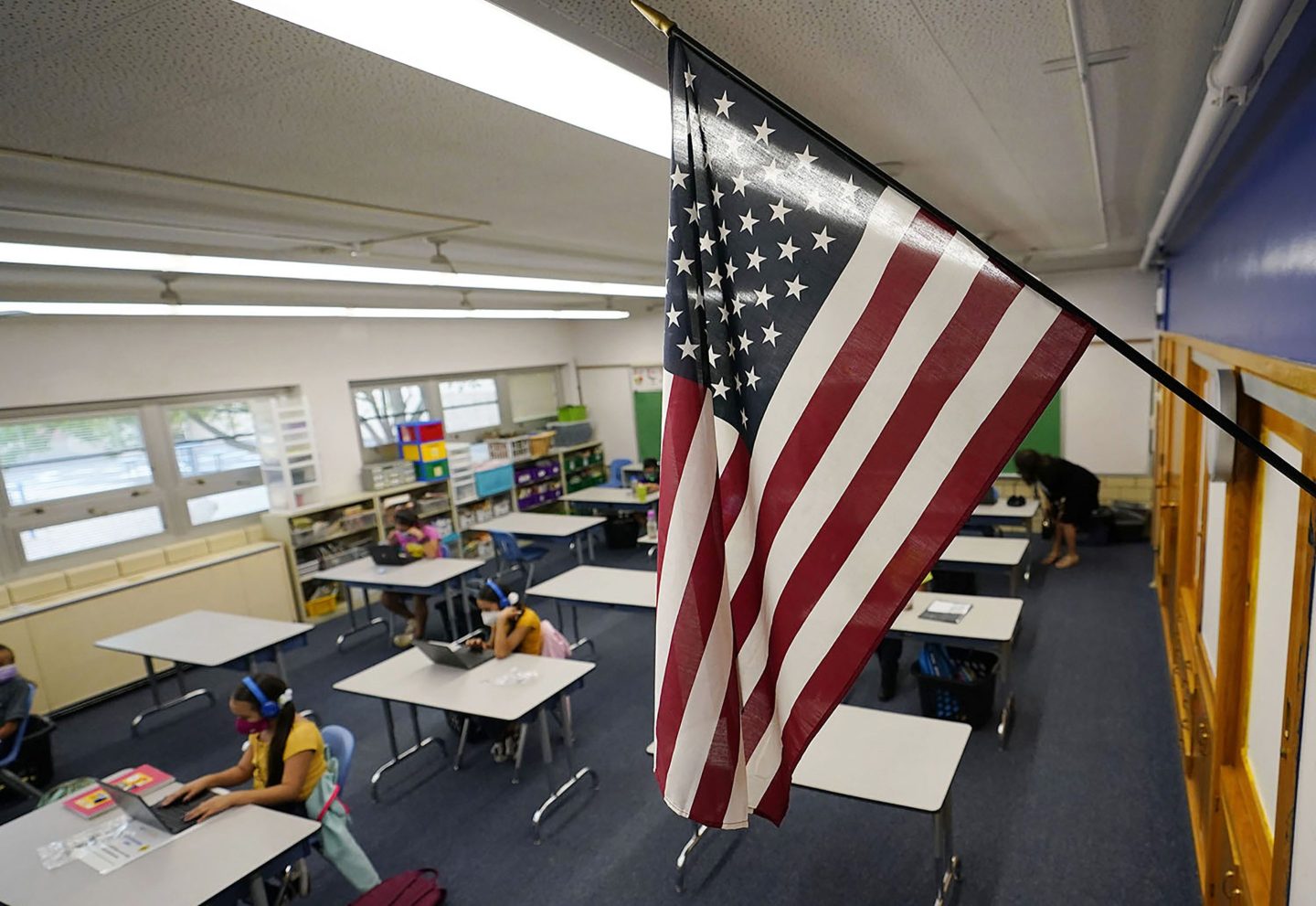 An American flag hangs in a classroom as students work on laptops in Newlon Elementary School, in Denver, Aug. 25, 2020.