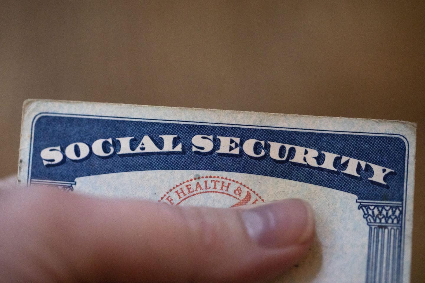 A person holds their finger over the personal information listed on a Social Security card