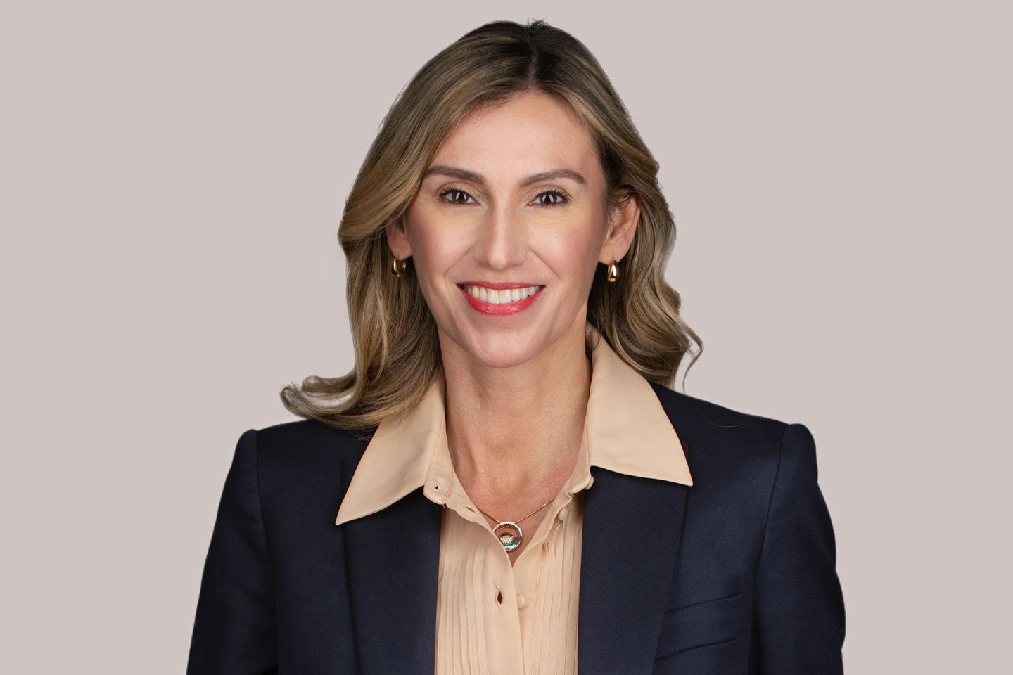 woman in suit jacket and collared shirt smiles for a photo portrait