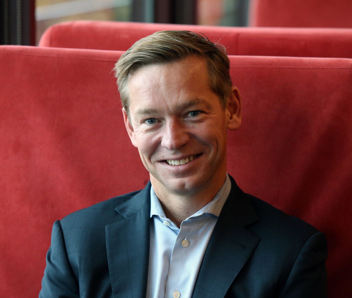 McDonald's CEO Chris Kempczinski poses while sitting in a red booth