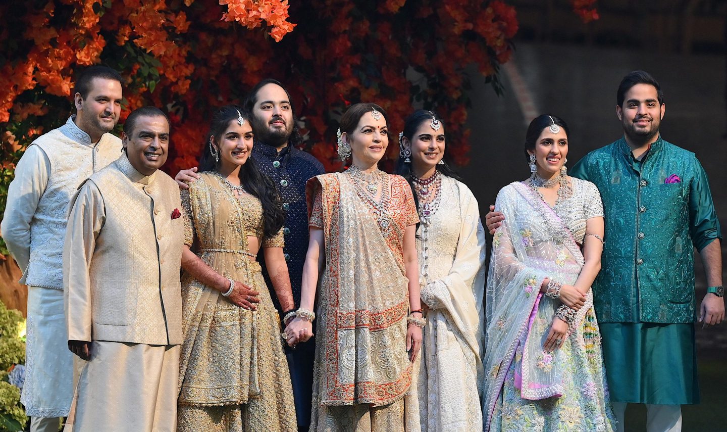 Indian billionaire Mukesh Ambani (2L) along with his wife Nita (4R) pose with their elder son Akash (R) his wife Shloka (2R), daughter Isha (3R) her husband Anand Piramal (L) and younger son Anant (4L) his fiancée Radhika Merchant (3L) during Anant's engagement ceremony in Mumbai on January 19, 2023. (Photo by Sujit JAISWAL / AFP)