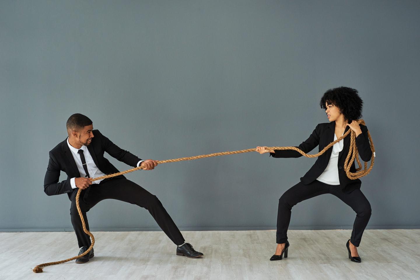 Two corporate workers playing tug of war.