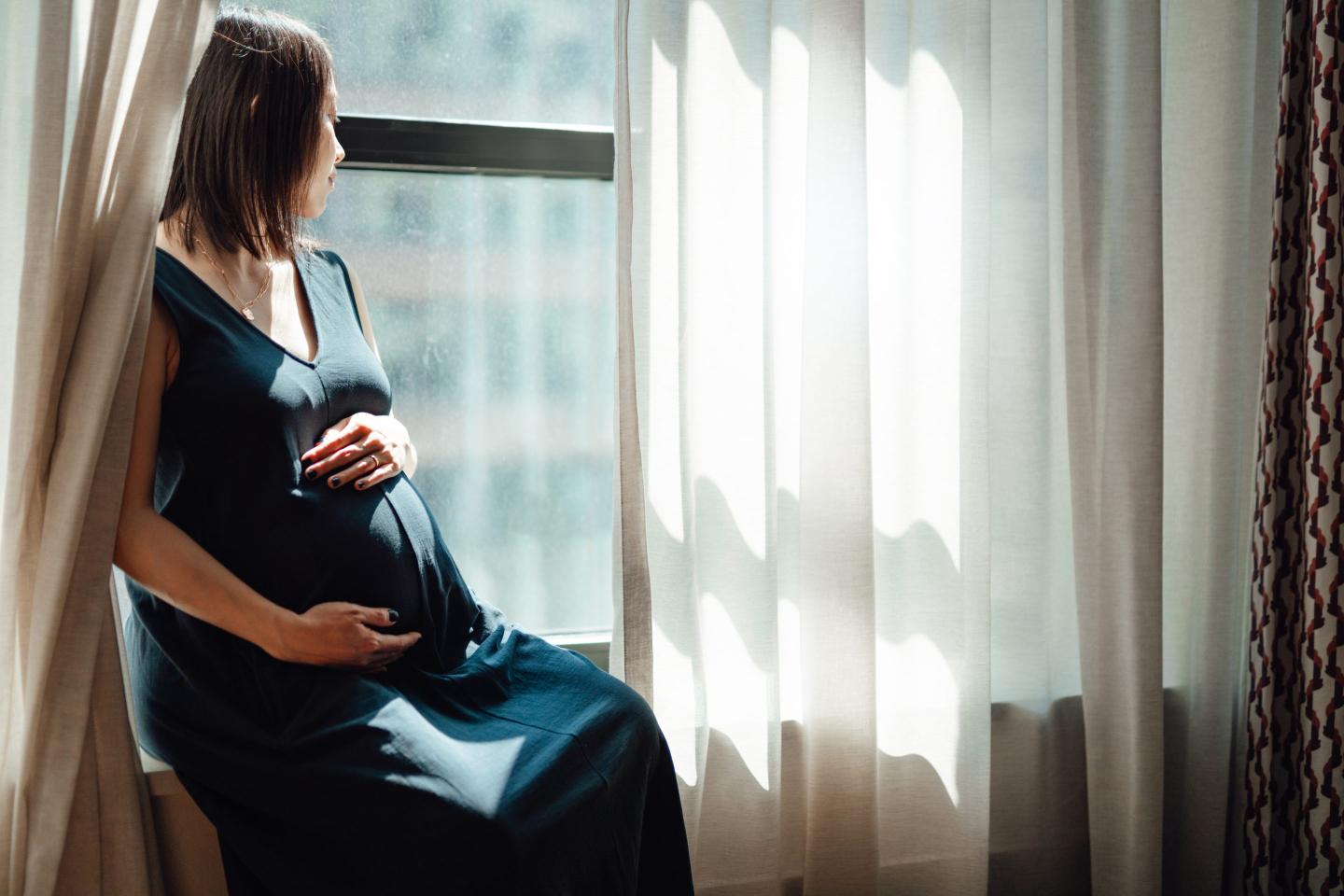 Pregnant woman looking out window