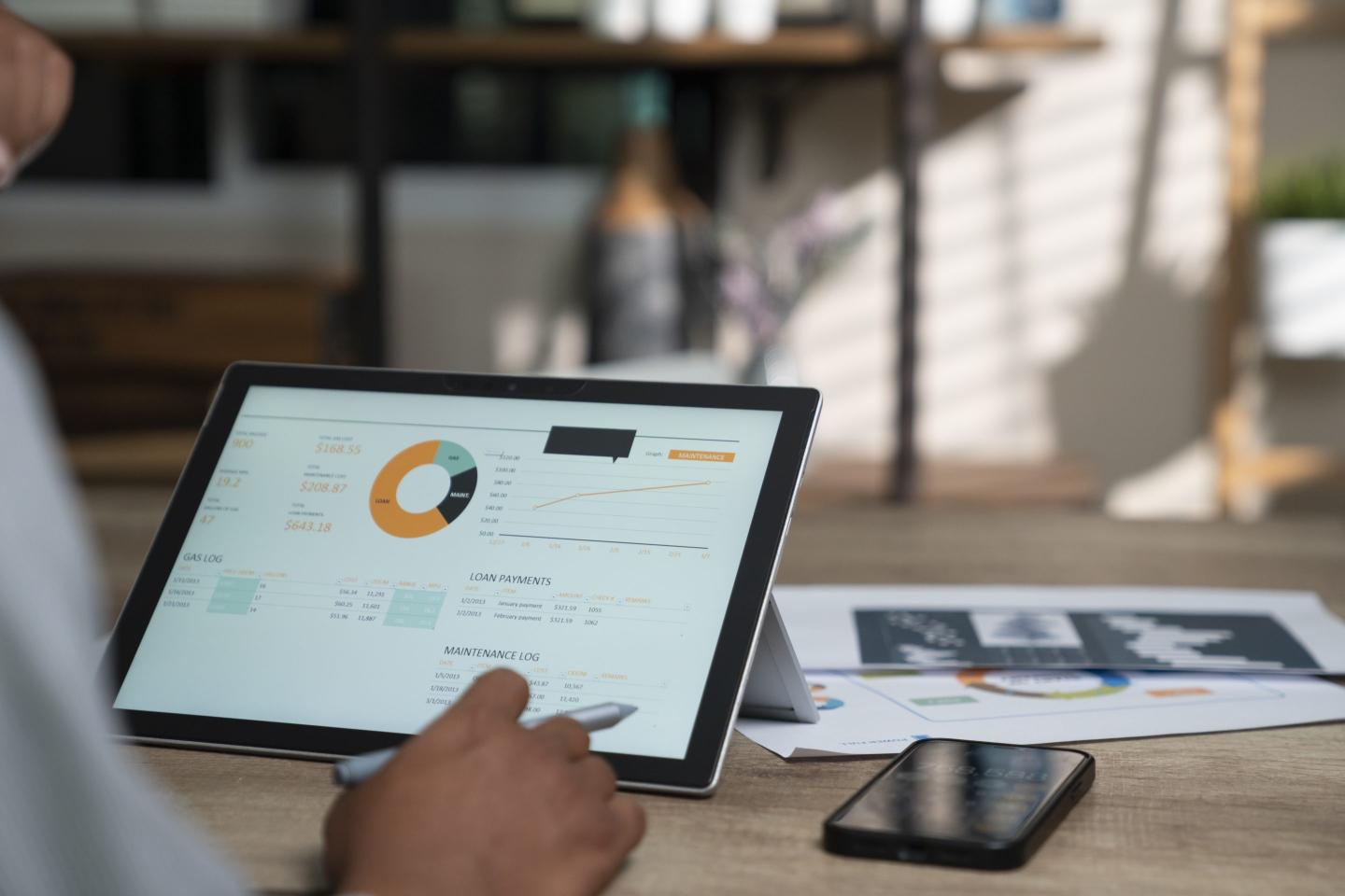 A person looking at financial dashboard on a tablet.