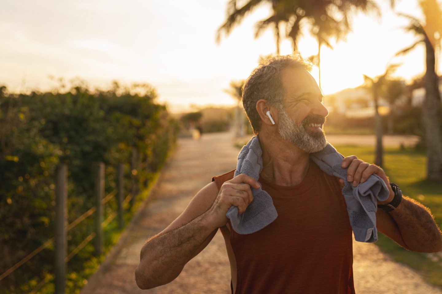 Closeup of man outside with earbuds and towel around neck, seemingly post-run