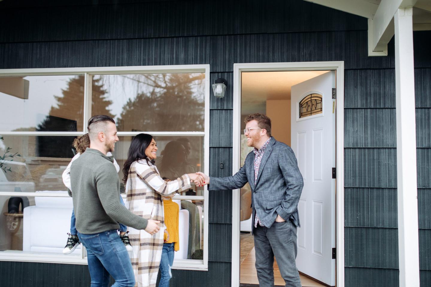 People shaking hands in front of a house.