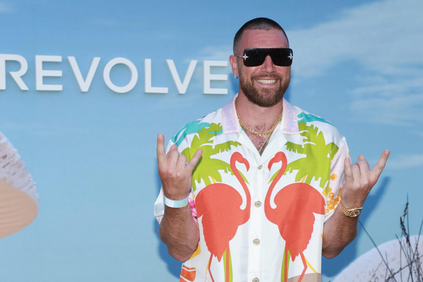 Travis Kelce wearing a Hawaiian shirt, sunglasses, and gold jewelry