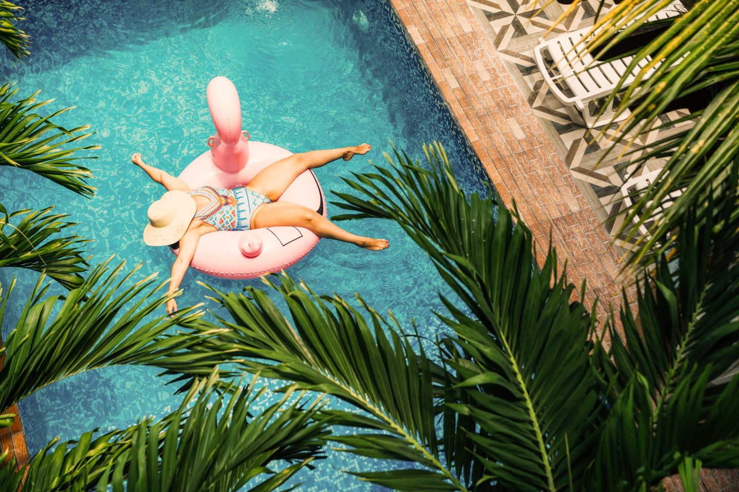 An aerial view of a person floating on a flamingo tube in a hotel pool.