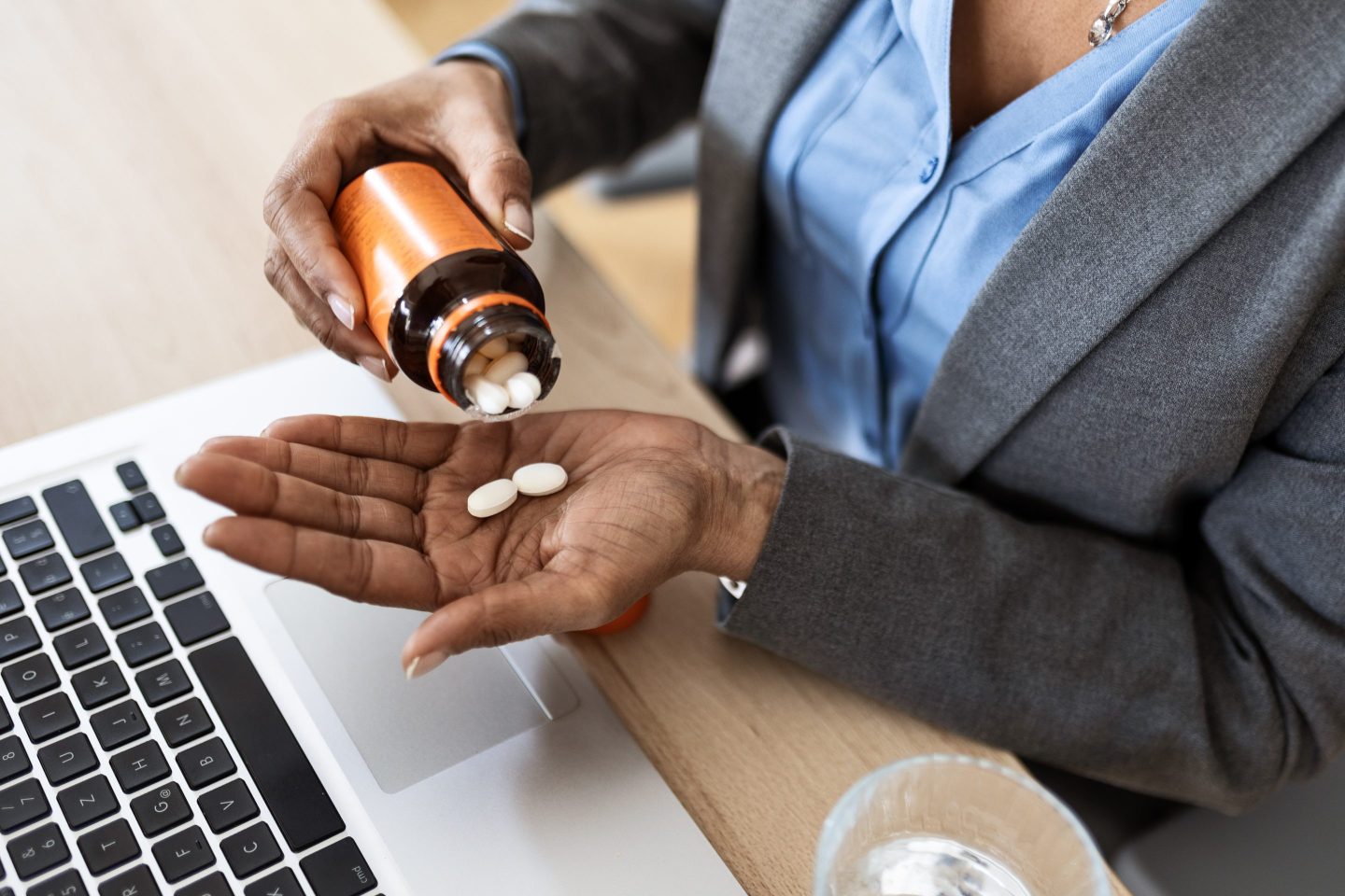 A woman takes pills at her desk
